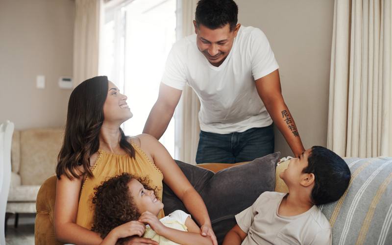 Pareja joven con sus dos hijos pequeños en el sofá de la casa
